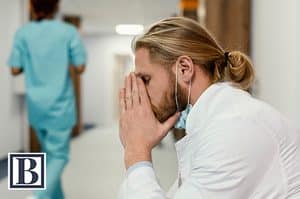 Stressed physician in a white coat and surgical mask covering his face in a hospital hallway, facing divorce and concerns about his medical practice