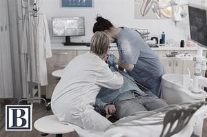 Dentist and dental assistant working with a patient in a dental practice treatment room
