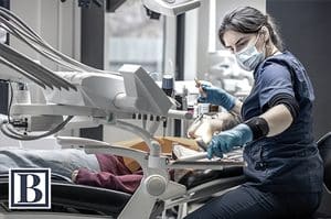 Dentist in a mask and gloves treating a patient in a modern dental office